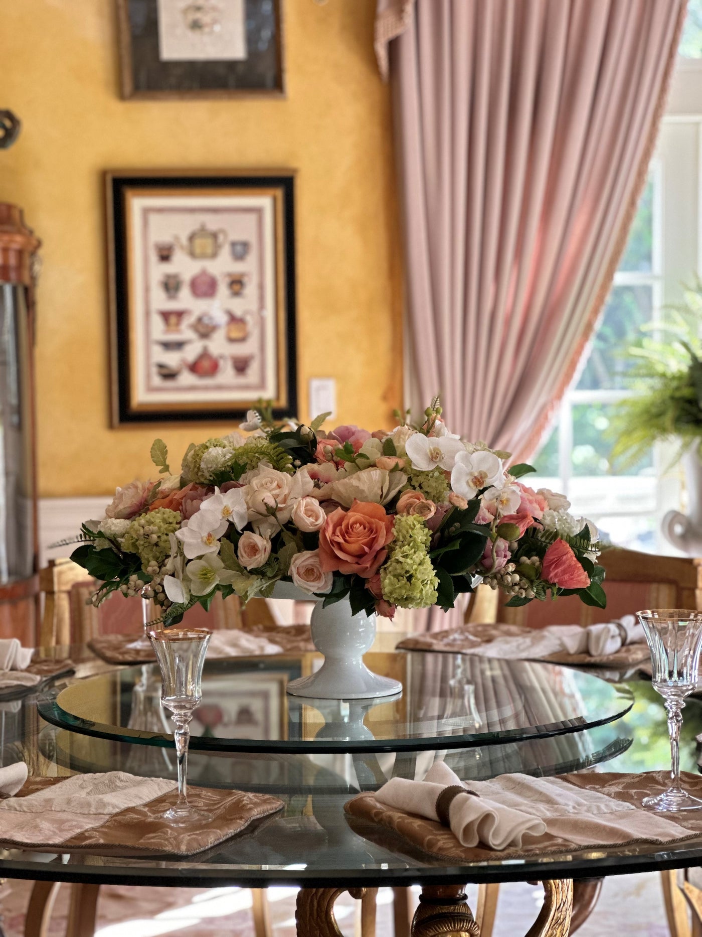 A sophisticated faux floral arrangement showcasing a blend of peonies, roses, orchids, and greenery in elegant shades of lavender, coral, and peach.